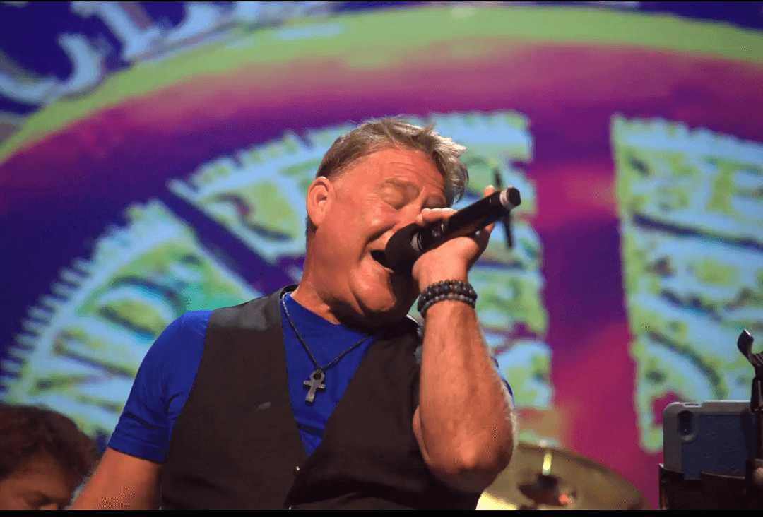 JC Grigg belting out vocals under stage lighting at the Chicago Revival show