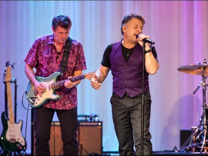 J.C. Grigg singing on stage beside guitarist Keith Howland